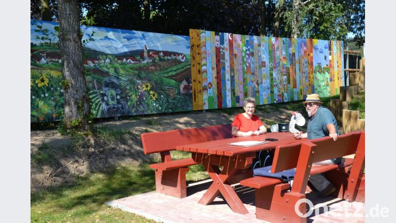 Ein 34 Meter langes Kunstwerk rahmt den Sassenreuther Spielplatz ein. Ein Teil stammt von Künstler Dieter Windisch (rechts). Die anderen Holzbretter haben mehrere Dorfbewohner bemalt. Die Idee dazu hatte Silvia Schecklmann (links). Bild: Anne Wiesnet