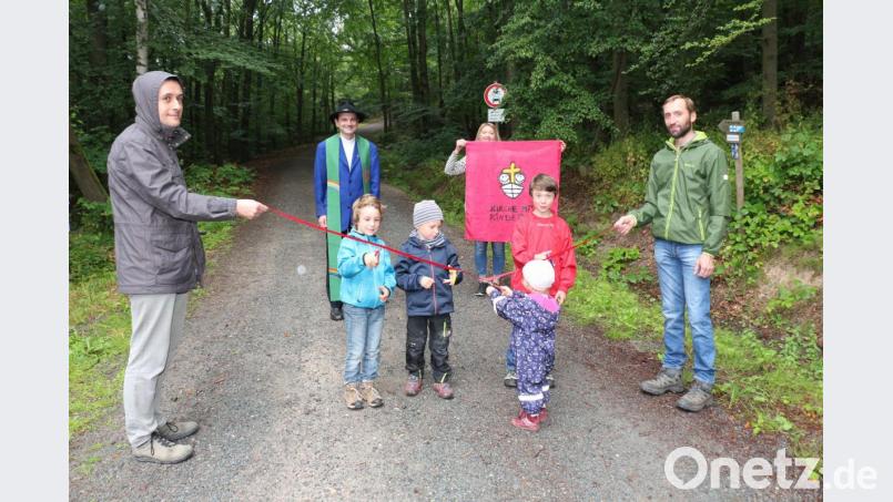 Einige Kindergottesdienstkinder haben sich trotz Regen eingefunden und warten gespannt, bis sie das rote Band durchschneiden dürfen. Bild: rpp