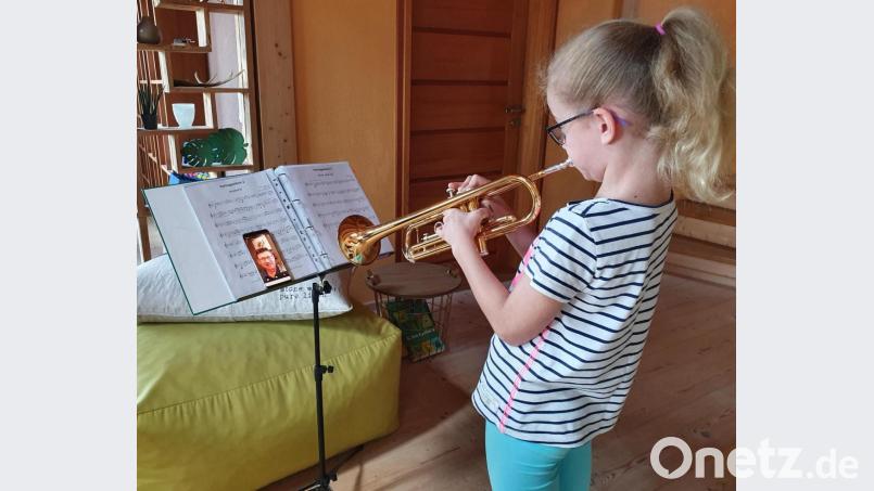 Musikunterricht per Whatsapp-Videoanruf: Mila Juraske (9) spielt das Stück auf der Trompete vor und Ausbilder Stefan Karl hört am Handy mit. Bild: Portner