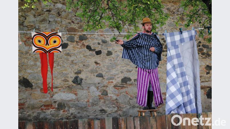 Der Bauer (Johannes Aichinger) kurz nach dem Aufstehen, noch im Schlafanzug. Links von ihm das bunte Huhn, rechts sein Bett. Bild: gge