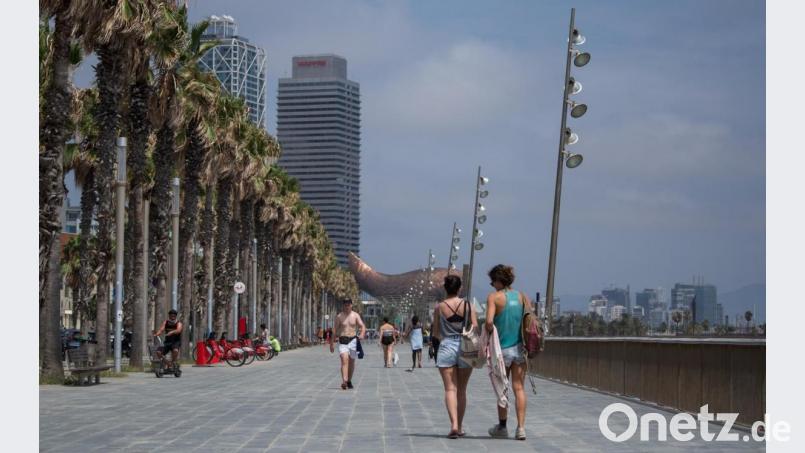 Zwei Frauen spazieren entlang der Strandpromenade in Barcelona. Das Auswärtige Amt warnt nun vor Reisen nach unter anderen Barcelona. Bild: Thiago Prudencio