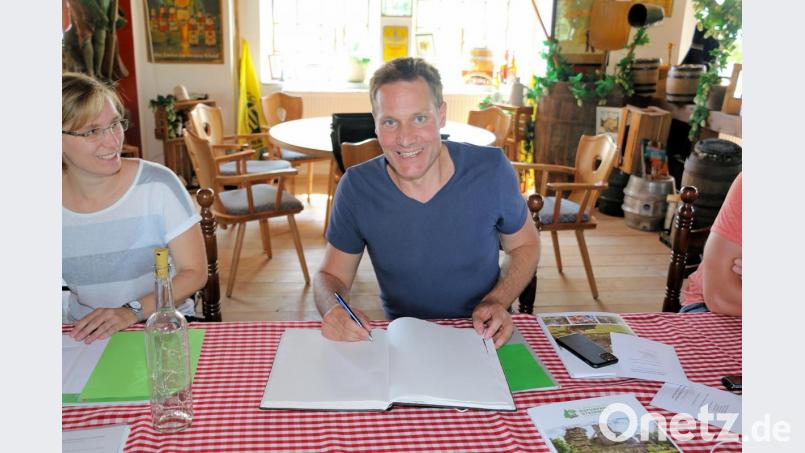 Ludwig Hartmann verewigt sich im Goldenen Buch der Gemeinde Friedenfels. Fremdenverkehrsamtsleiterin Melanie Höfer (links) freut sich über den Eintrag. Bild: bsc