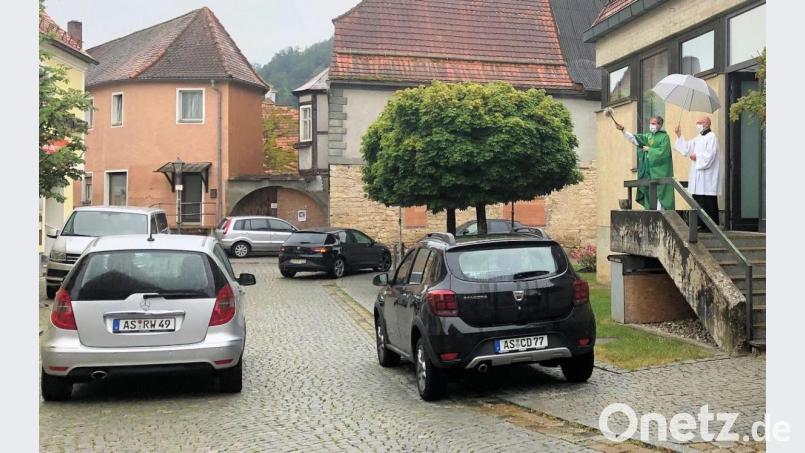 Pfarrer Werner Sulzer (rechts) segnet die vorbeifahrenden Autos mit Weihwasser. Bild: bjo