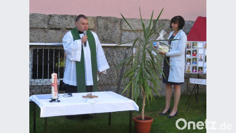 Nach der Andacht im Garten des städtischen Kinderhauses überreichte Einrichtungsleiterin Susi Fellner im Namen des Personals und der Kinder ein Präsent an den scheidenden Kaplan Matthias Nowotny. Bild: Städtisches Kinderhaus Mitterteich/exb
