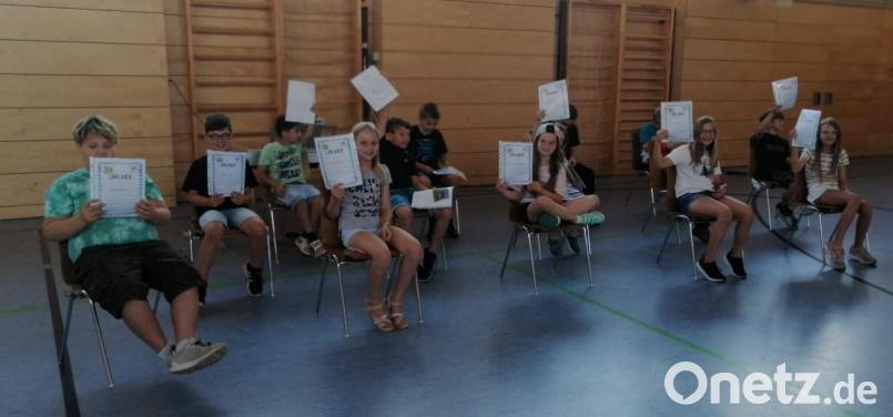 Die Klasse 4b mit ihren Zeugnissen bei der feierlichen Verabschiedung der Grundschüler in der Mehrzweckhalle Bild: mez