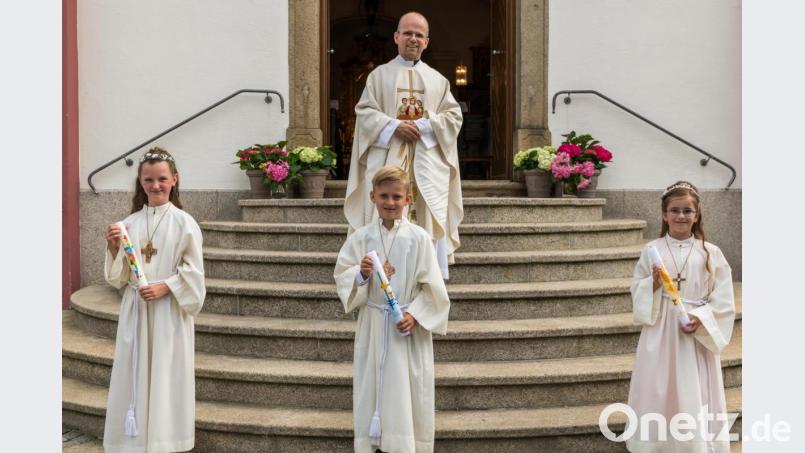 Die drei Mähringer Kommunionkinder Amelie Müller, Sebastian Weber und Alina Müller (von links) mit Pfarrer Armin Maierhofer. Bild: wms
