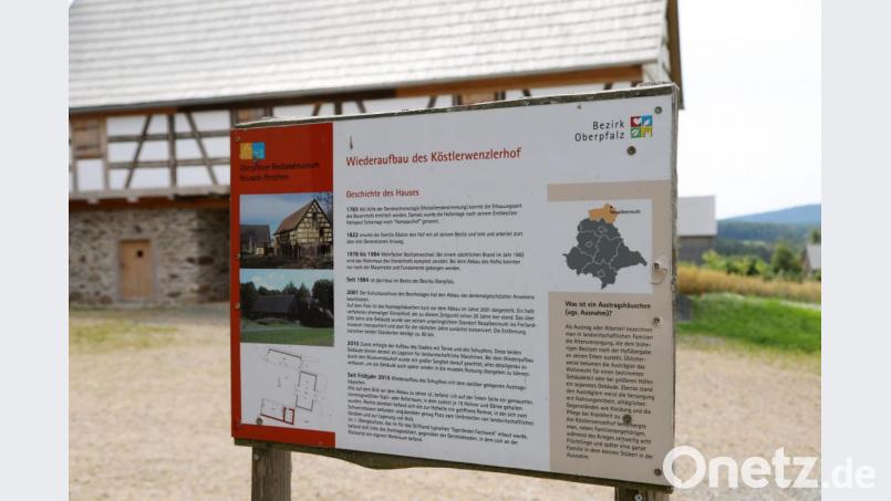 Auf der Fläche zwischen der Infotafel, auf der der Köstlerwenzlhof unter dem Namen Köstlerwenzlerhof geführt wird, und dem Gebäude im Hintergrund entsteht das neue Bauernhaus. Bild: Gerhard Götz