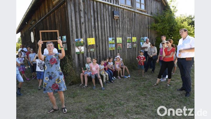 Das mehrtägige Ferienprogramm „Malen im Freien“ mit Dorothe Pfeiffer (stehend, vorne) von der Werkstatt für Kinder kam bestens an: Bei der Abschlusspräsentation auf dem Gelände der Umweltwerkstatt Amberg (UWA) zeigten die Kinder ihren Eltern die selbstgemalten Motive (im Hintergrund an der Scheune). Bild: Petra Hartl