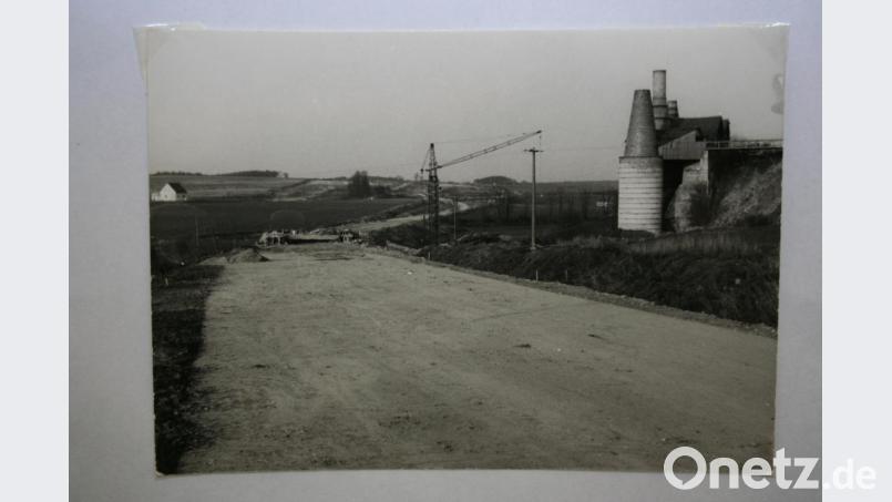 Das Bild zeigt wie die B 470 aus Richtung Auerbach zum Schönsteiner Berg verläuft. Rechts die Kalköfen, der vordere wurde als Denkmal erhalten. Vorne arbeitet man an der Brücke, unter der das Gleis von den Kalköfen und dem Steinbruch (rechts) zur Kalkmühle zum Verladebahnhof verläuft. Archivbild: gpa