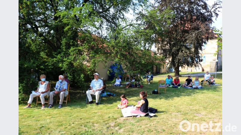 Die Gottesdienstbesucher verteilen sich für den Picknick-Gottesdienst im Pfarrgarten. Wegen der kräftigen Sonne sind die Schattenplätze schnell belegt. Bild: rpp