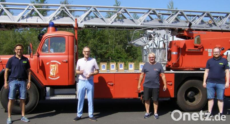 Bürgermeister Bernd Sommer, &quot;Hausherr&quot; des Feuerwehrgerätehauses, bekam den ersten der Pokale, die die Feuerwehr den Teilnehmer der Oldtimer-Treffen in den vergangenen Jahren schicken wird. Von links Kommandant Tobias Tippmann, Bürgermeister Bernd Sommer, Feuerwehr-Vorsitzender und Feuerwehrarzt Dr. Wolfgang Fortelny und stellvertretender Vorsitzender Sebastian Koch vor einer historischen Drehleiter aus dem Fuhrpark der &quot;Fo-Wehr&quot;, auf der einige der Pokale aufgestellt waren. Bild: pz