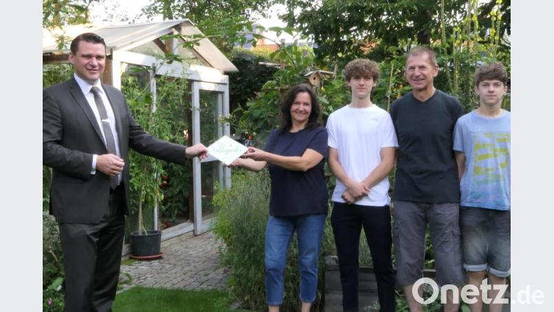 Landrat Thomas Ebeling (links) überreicht der Familie Andrea und Josef Fischer aus Schwarzenfeld die Auszeichnung „Bayern blüht – Naturgarten“. Bild: Wolfgang Grosser/exb