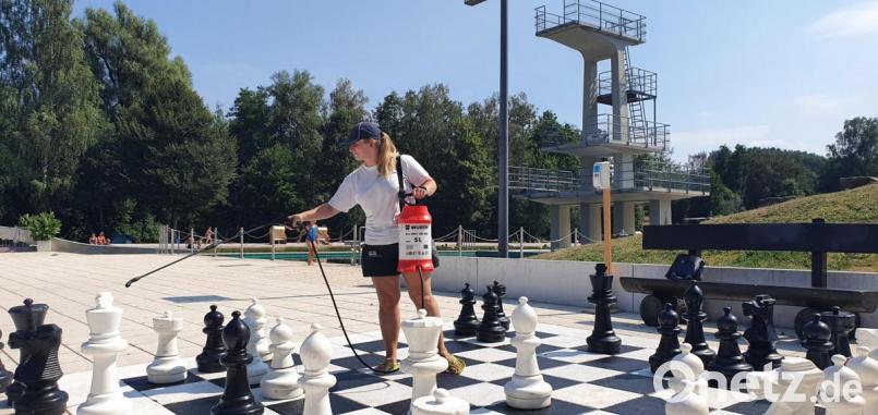 Bademeisterin Melanie Kastner beim täglichen Desinfizieren der Schachfiguren im Marktredwitzer Naturbad. Auch alle anderen Spielgeräte werden regelmäßig vom Reinigungspersonal saubergemacht. Bild: Peggy Biczysko/fph