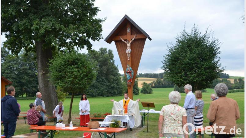 Vor dem Dorfkreuz versammeln sich die Gläubigen mit Dekan Alexander Hösl zum Gottesdienst. Die gesellschaftliche Feier dagegen muss ausfallen. Die Teilnehmer hatten auf dem Dorfplatz viel Raum um den geforderten Abstand einzuhalten. Bild: dob