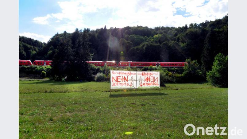 „Bahnstromtrasse Nein – Rettet das Lehental“ steht auf Transparenten, die Bürger an mehreren Stellen rund um Oed (Weigendorf) aufgestellt haben. Dahinter fährt ein dieselbetriebener Regionalexpress der Bahn. Um die Züge mit Strom zu betreiben, will die Bahn eine Stromtrasse in die teils geschützte, naturbelassene Landschaft bauen. Bild: Stephan Huber
