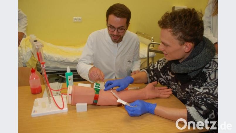 Dieser Arm ist schon oft gepikst worden: Medizinstudent Lucas Rüffer übt die Blutabnahme. Dahinter Tutor Johannes Gludowatz. Das Bild stammt aus Vor-Corona-Zeiten, aktuell pausieren die Kurse. Bild: gib