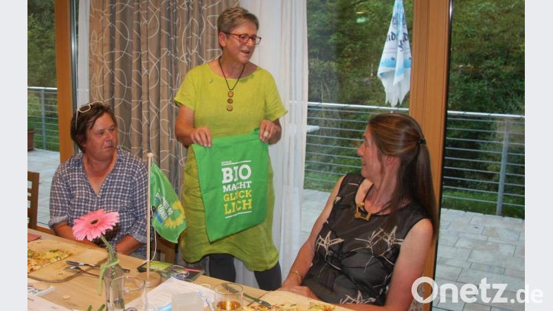 Das Tischbanner soll den künftigen Grünen-Stammtisch schmücken. Damit, zudem mit „Bio-Einkaufstaschen“ beschenkte die Kreisvorsitzende Heidrun Schelzke-Deubzer das weibliche Vorstands-Duo Lisa Rau aus Friedenfels (links) und Simone Bloemhof aus Pfaben (rechts). Als weitere Überraschung wurde nach der Versammlung auch eine &quot;Grünen-Torte&quot; angeschnitten, die die Siegritzerin Ursula Stocker gebacken hatte. Bild: wro
