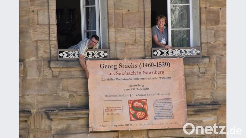 Maria Müller (rechts), neue Vorsitzende des Trägervereins der Historischen Druckerei J. E. v. Seidel und ihr Vize Stadtheimatpfleger Markus Lommer, die am Seidel/Wotschack-Anwesen das druckfrische Werbebanner zur Stuchs-Ausstellung aufhängen. Bild: Andreas Royer