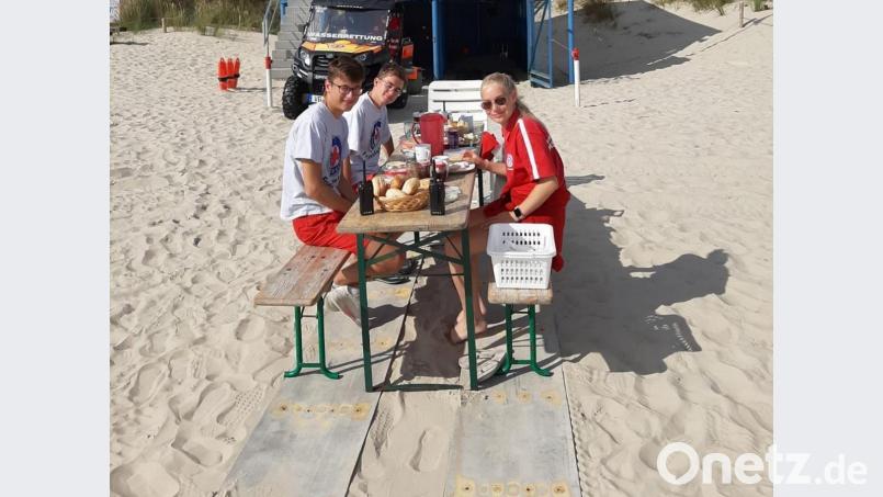 Justin Hausknecht und Bastian Münchmeier (von links) aus Friedenfels mit Zoe aus Magdeburg beim Frühstück am Strand von Usedom. Bild: Wasserwacht Friedenfels/exb