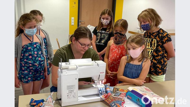 Claudia Zeitler zeigt den Kindern die richtige Bedienung der Nähmaschine und auf was sie achten müssen. Bild: nza