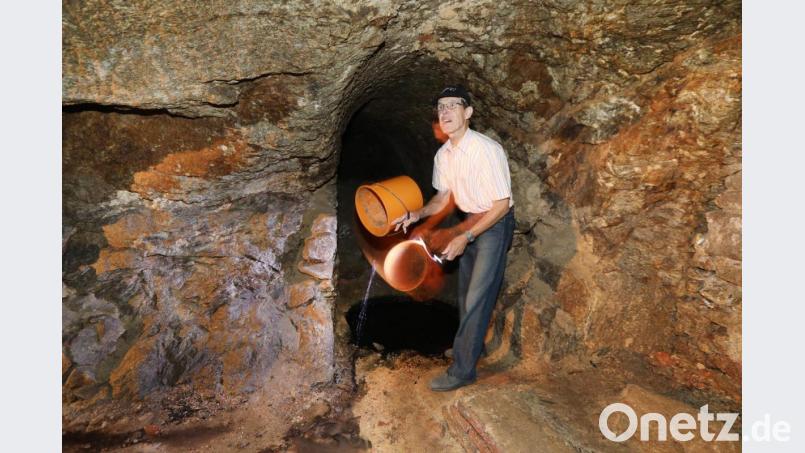 Johann Köppl demonstriert mit einem Eimer, wie klar das Wasser ist, das sich hier im Felsenkeller unter dem ehemaligem Schloss in Dieterskirchen sammelt. Bild: Gerhard Götz