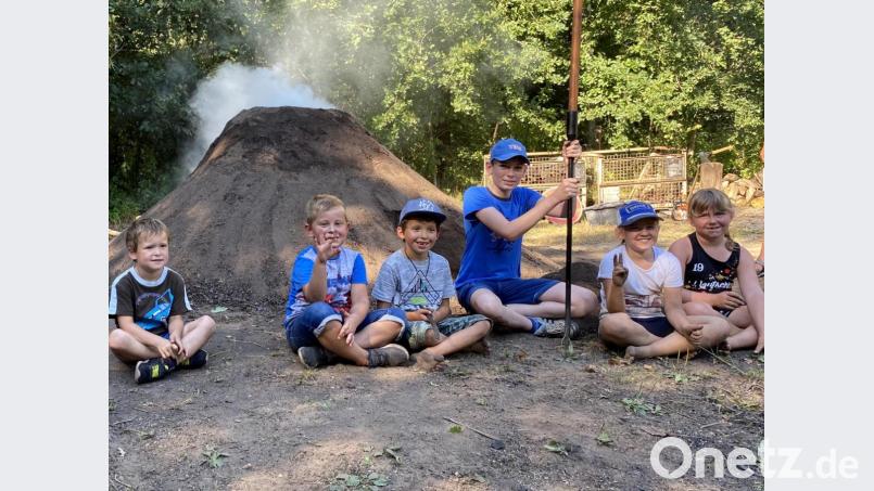 Glücklich und erschöpft freuen sich die Nachwuchs-Köhler über den weißen Rauch, der aus ihrem Kinder-Kohlenmeiler nach der harten, schweißtreibenden Arbeit quillt. Bild: wec