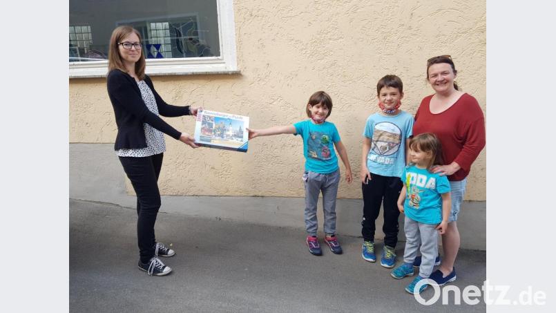 Sabrina Reiner (links) vom Kreisjugendring überreicht als Hauptpreis ein 1000-teiliges Schwandorf-Puzzle an die Gewinner-Familie aus Pfreimd. Bild: hir
