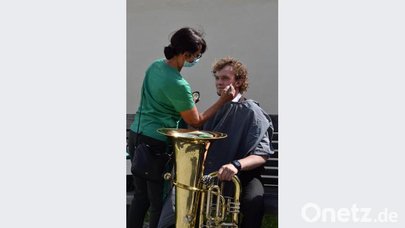Nacheinander dürfen die acht Musiker der Musikgruppe noch in der Maske, sie werden auf einer Parkbank noch schnell gepudert. Bild: szl