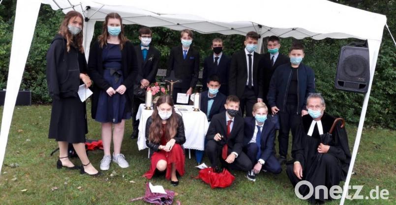 Zum Gruppenfoto suchen die zwölf Rosenberger Konfirmanden und Pfarrer Uwe Markert unter einem Pavillon Schutz vor dem Regen, der am Sonntag unaufhörlich auf den CVJM-Sportplatz herunterprasselt. Bild: exb