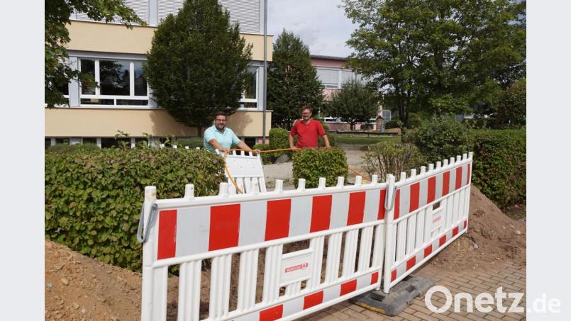 Bürgermeister Thomas Kaufmann (links) und Polier Martin Lindner (rechts) freuen sich über den schnellen Baufortschritt. Das Glasfaserkabel für das Leerrohr in der Johann-Baptist-Blas-Straße halten sie an der Baugrube auf dem Schulgelände in der Hand. Bild: bkr
