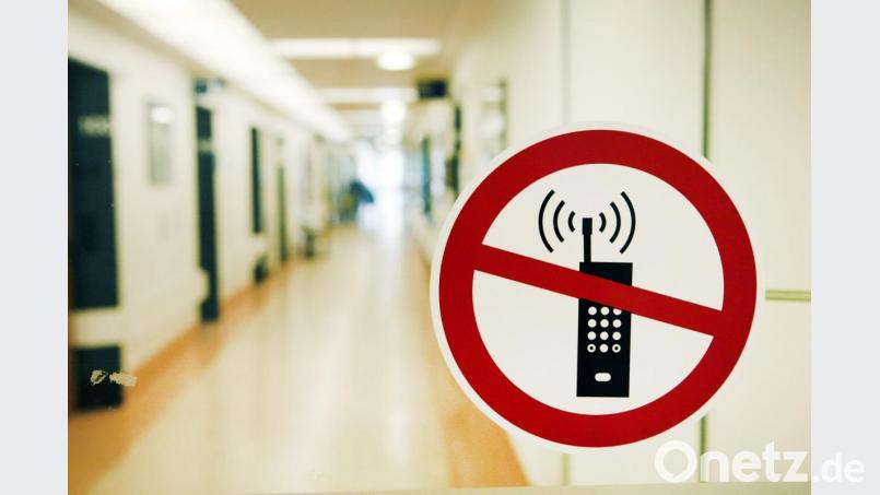 Ein Handy-Verbotsschild klebt an der Glastür eines Krankenhauses. In den meisten Bereichen darf trotzdem telefoniert werden, doch Patienten müssen in ländlichen Regionen auch mal damit rechnen, dass sie kein Netz haben. Symbolbild: Sebastian Widmann/dpa