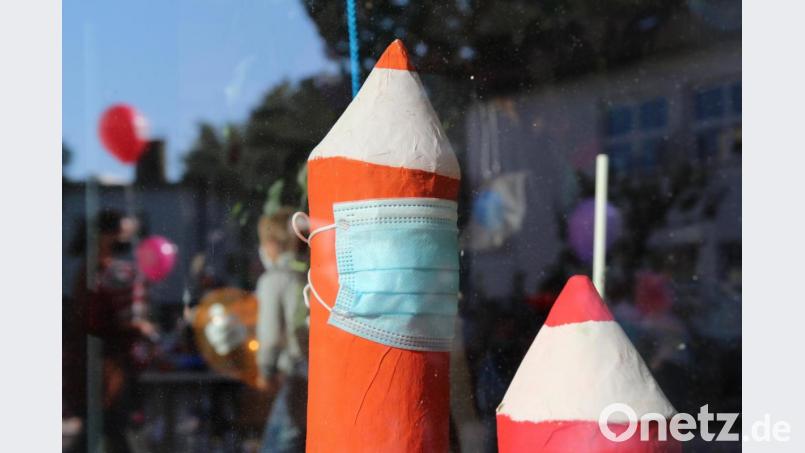 Beim Schulstart in Neustadt/WN. Ein Stift, der im Schulhaus ausgestellt ist, trägt einen Mundschutz. Vor der Schule lassen Erstklässler mit ihren Eltern Luftballons steigen. Sie spiegeln sich in der Fensterscheibe. Bild: sfo