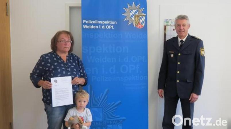 Hannelore Schönberger nimmt gemeinsam mit ihrem Enkel Johannes das Dankesschreiben des Oberpfälzer Polizeipräsidenten von Inspektionsleiter Klaus Müller entgegen. Der Polizeipräsident lobte ihr beherztes Eingreifen. Bild: Polizei Weiden