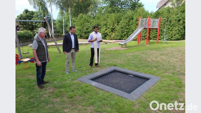 Bürgermeister Wolfgang Söllner, Pfarrer Pater Anish George und „Bauleiter“ Hubert Becher bei der Einweihung der neuen Spielgeräte. Hier das neue Bodentrampolin. Bild: soj