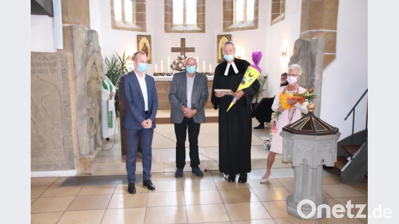 Die Vertrauensmänner der beiden Kirchenvorstände (von links), Michael Kuhn für Rosenberg und Wolfgang Böttner für Poppenricht, schenken Pfarrer Uwe Markert zum Abschied eine Schultüte und seiner Frau Kristina Blumen. Bild: cog