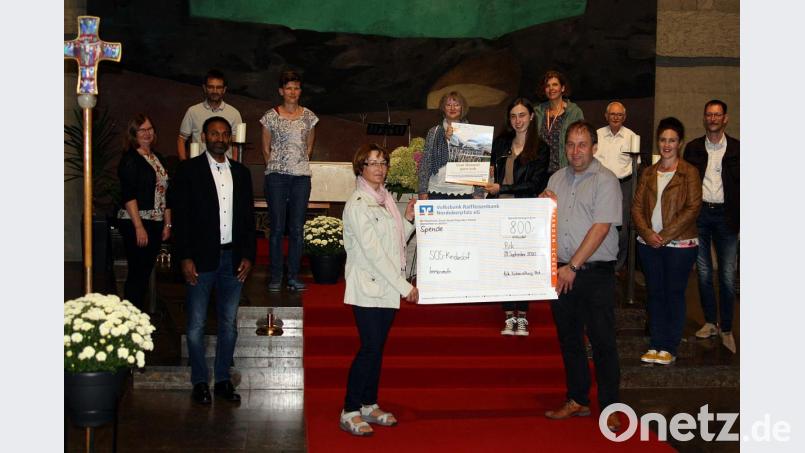 Die Mitwirkenden, Organisatoren, Oberministranten und Familiengottesdienstmitglieder überreichten eine Spende aus einem interessanten Kinogottesdienst über 800 Euro an das SOS-Kinderdorf. Links: Pfarrer Jaison Thomas und Holger Hassel der symbolisch den Scheck hält. Bild: zer