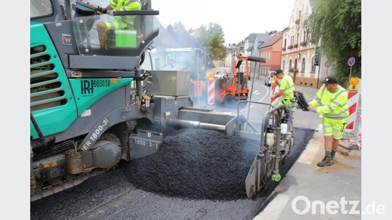 Der heiße Asphalt wird mit Hilfe einer schweren Maschine verarbeitet. Bild: kro