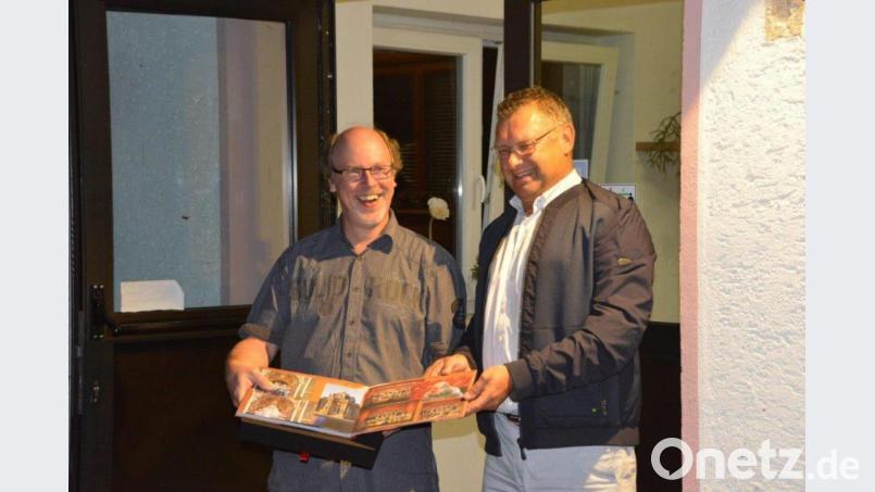 Mit einem Erinnerungsalbum gratulierte der Vorsitzende des Amberger Oratorienchors, Wolfgang Streich (rechts), Chorleiter Thomas Appel (links) zum Silbernen Dienstjubiläum. Bild: Günter Hummel