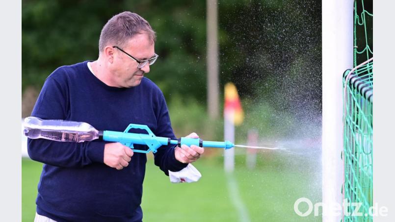 Eine Kinder-Spritzpistole und eine alte Cola-Flasche hintendran, gefüllt mit Desinfektionsmittel: Theuerns Vereinsvorsitzender Christian Schrott demonstriert, wie mit der Spritze zum Beispiel die Torpfosten desinfiziert werden. Ebenso die Hütchen im Training, und noch einige andere Dinge. Die Fußbälle werden mit Tüchern abgewischt. Bild: ref