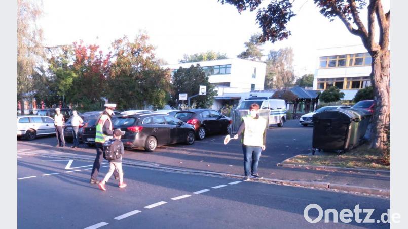 Polizeimeisterin Anwìn Selina Dirrigl unterstützt einen Abc-Schützen mit Hilfe eines Schülerlotsens beim sicheren Überqueren der Fahrbahn vor der Willmannschule in Amberg. Bild: Polizei Amberg