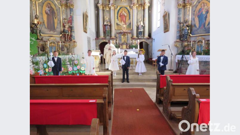 Nach der Kirche präsentieren sich die Kommunionkinder mit Pfarrer Pennoraj Tharmakkan (hinten) vor dem Altar. Bild: adj