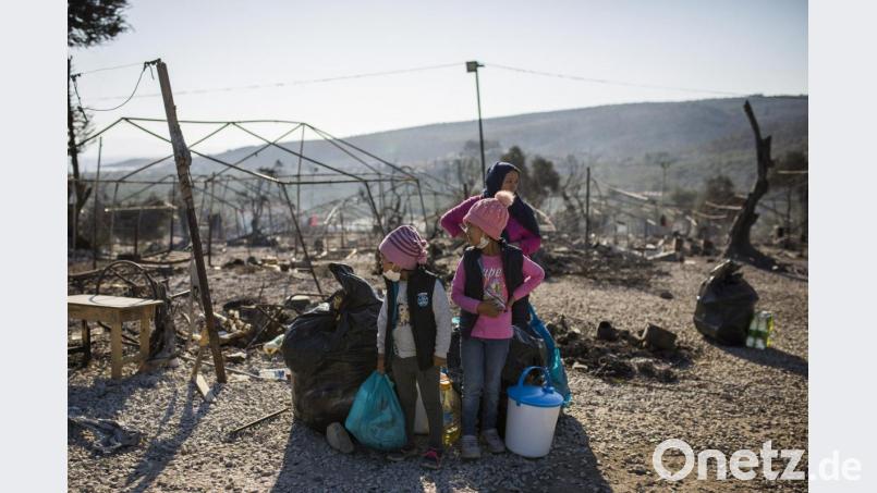 Eine Familie steht innerhalb des ausgebrannten Flüchtlingslagers Moria. Mehrere Brände haben das Lager fast vollständig zerstört. Bild: Socrates Baltagiannis/dpa
