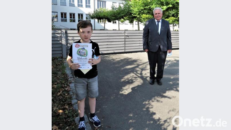 Der neunjährige Christoph hat in sechs Wochen 86 Bücher gelesen. Stolz präsentiert er seine Urkunde, Zweiter Bürgermeister Peter Gold grautliert. Bild: ubb