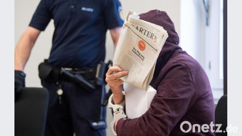 Am Mittwoch, 23. September 2020, vor dem Landgericht Stuttgart: Der Angeklagte in einem Mordprozess, der 25 Jahre nach der Tat beginnt, sitzt in einem Saal des Landgerichts und hält sich eine Zeitung vor sein Gesicht. Bild: Marijan Murat/dpa