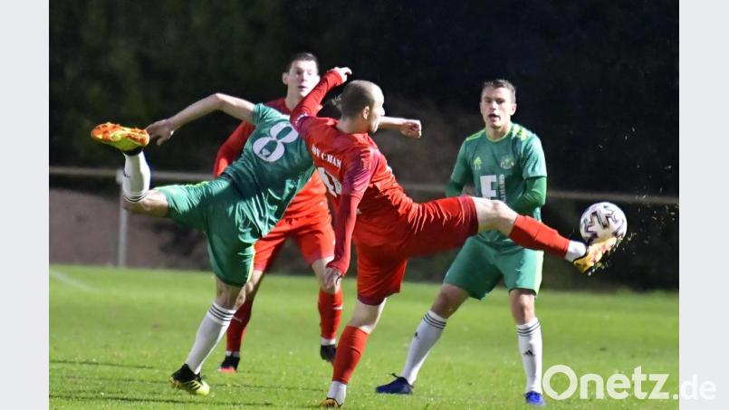 Mit einem Spagatschritt ist der für den ASV Cham spielende Ex-Ammerthaler Friedrich Lieder (rechts im roten Trikot) vor dem DJK-Innenverteidiger Marius Dimmelmeier (links) im Zweikampf am Ball. Die Szene beobachtet rechts der Ammerthaler Julius Hammer. Bild: Hubert Ziegler
