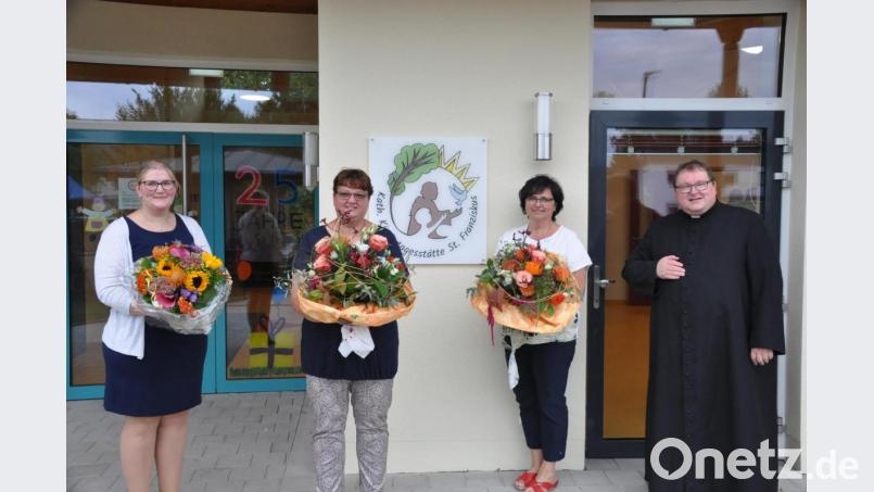 Mit Blumen bedankte sich Pfarrer Sven Grillmeier bei Barbara Reichenberger und Sabine Leibl, die seit 25 Jahren zum Personal der Kindertagesstätte Sankt Franziskus gehören, sowie bei Leiterin Sabine Pöllath (von rechts). An der Wand ist das neue Logo der erweiterten Kindertagesstätte zu sehen. Bild: ak