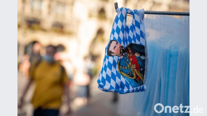 Mundnasenschutzmasken mit dem Konterfei König Ludwig II. werden an einem Kiosk vor dem Rathaus am Marienplatz, im Herzen der bayerischen Landeshauptstadt, verkauft. Bild: Peter Kneffel/dpa