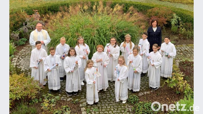 Pfarrer Markus Bruckner und die stellvertretende Schulleiterin der Grundschule, Kerstin Zaus, zusammen mit den 14 gut gelaunten Erstkommunikanten im Pfarrgarten der Herz-Jesu-Pfarrei. Bild: mez