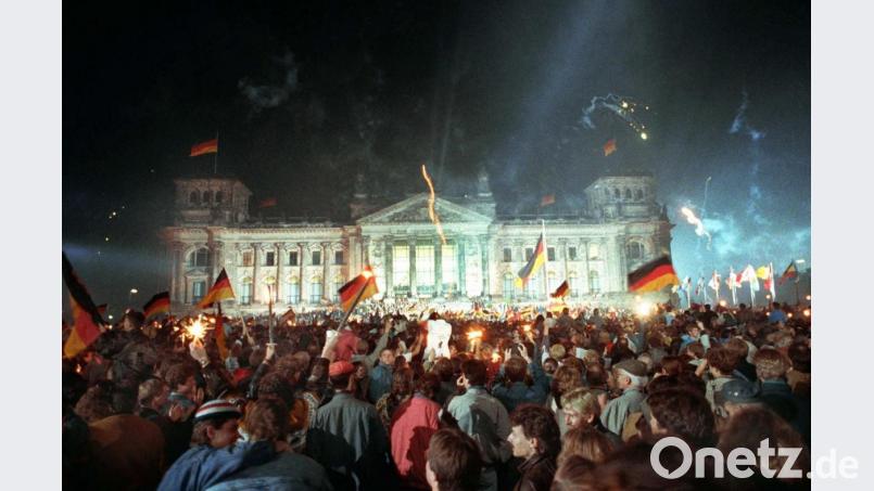 3. Oktober 1990, Berlin: Jubelnde Menschenmassen vor dem Berliner Reichstag, die mit Feuerwerk, Deutschlandfahnen und Volksfesttrubel die wiedergewonnene Einheit Deutschlands feiern. Archivbild: Jörg Schmitt/dpa