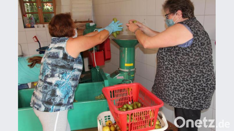 Erika Saalfrank (links) und Elfriede Berling befüllen den Apfelschredder mit Äpfeln. Bild: kro